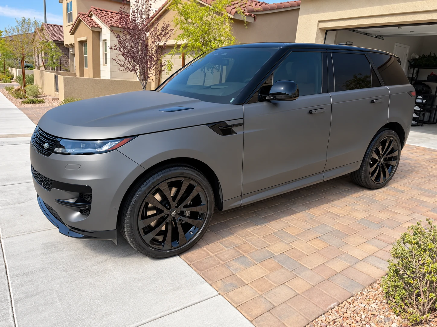 Satin gray Range Rover Sport with a black roof and black wheels on a paver driveway
